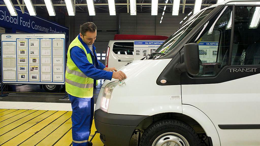 An employee checks the bonnet of a completed white Ford Transit van as it moves along the production line at the Ford Otosan plant,in Turkey in 2013.