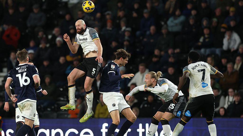 Matt Clarke goes up for a header with a Millwall player