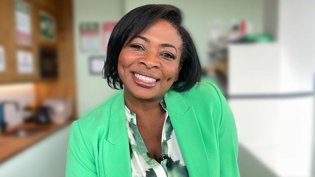 Lawyer Denise Nurse wearing a green suit jacket with a green and white marble shirt on underneath, sat in the Morning Live green room