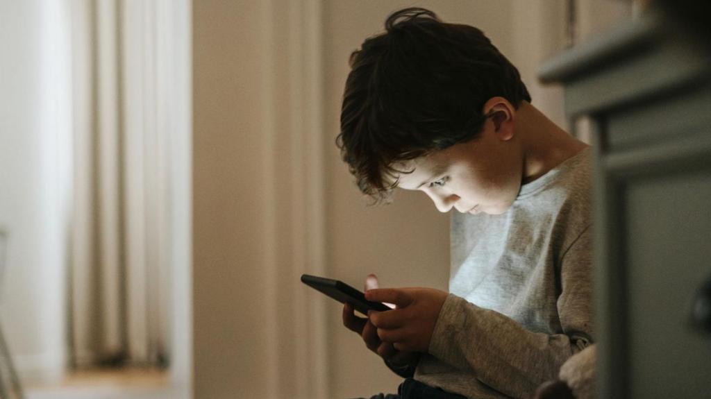 A young boy sat down staring at a smart phone screen 