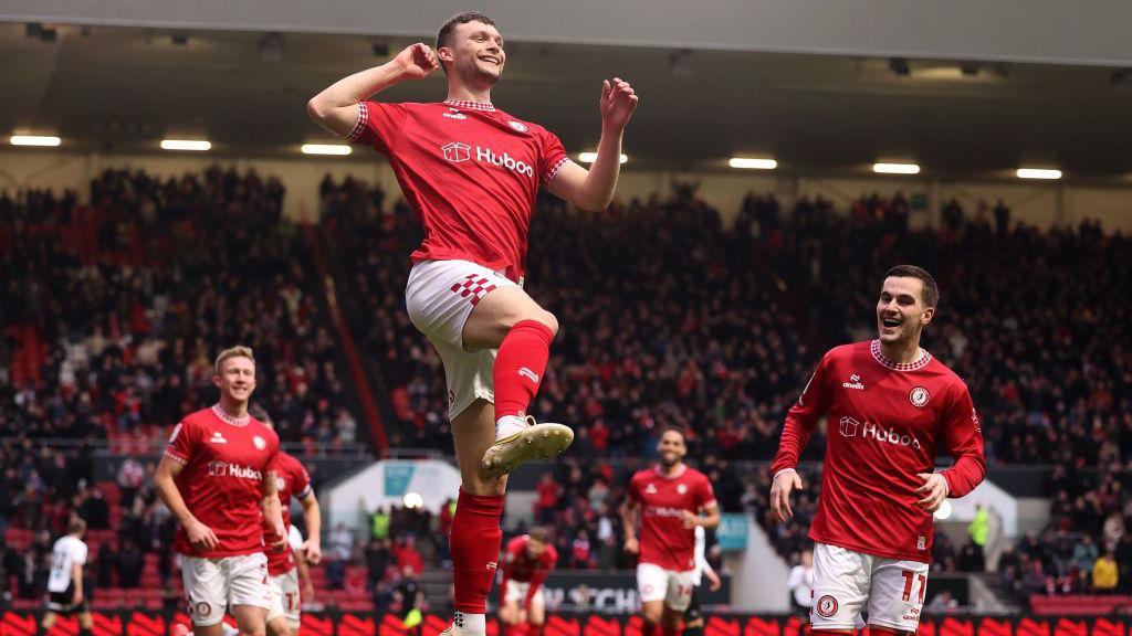 Luke McNally jumps in the air in celebration after scoring a goal