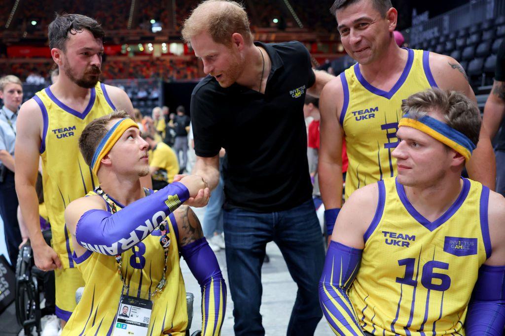 A man in a wheelchair shakes Prince Harry's hand