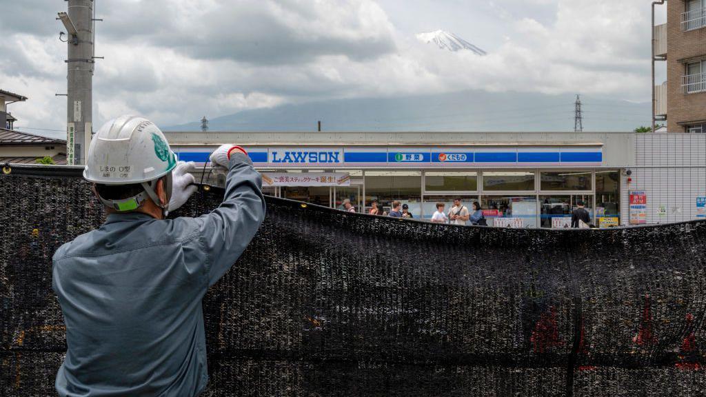 A worker installs a barrier to block the sight of Japan's Mount Fuji