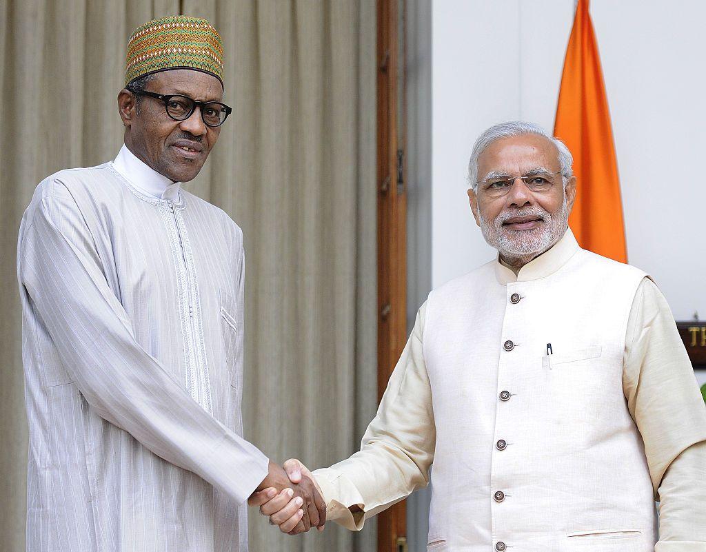 Muhammadu Buhari and Narendra Modi, both wearing white outfits, shake hands at a formal photo opportunity.
