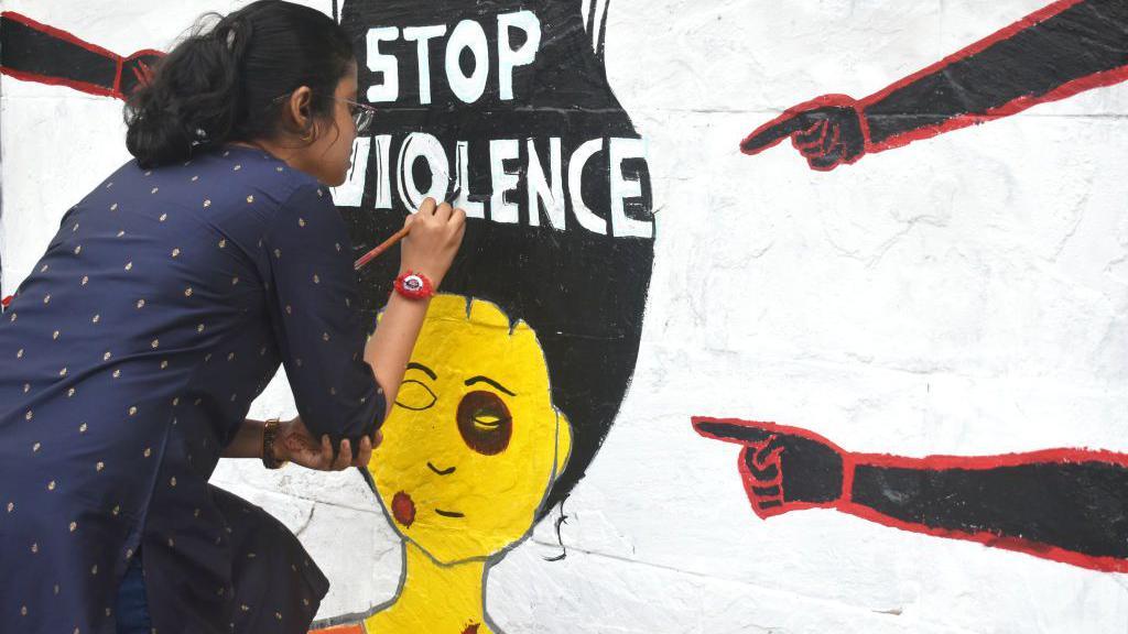 A doctor is painting a mural with slogans inside Kolkata Medical College and Hospital campus condemning the rape and murder of a trainee medic at a government-run hospital, in Kolkata, India, on August 19, 2024