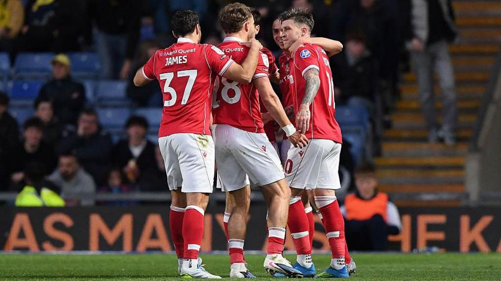 Wrexham players, including Matty James, celebrate with goalscorer Josh Windass in a huddle 