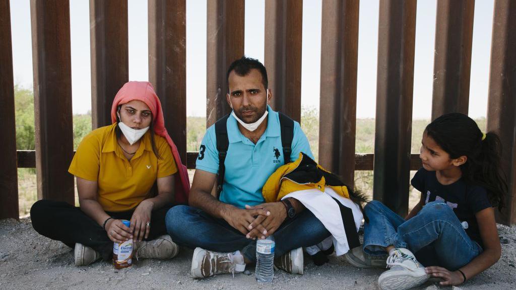 A family from India seeking aslyum in the US rests at the border with Mexico, in Yuma Arizona, USA, 20 May 2022