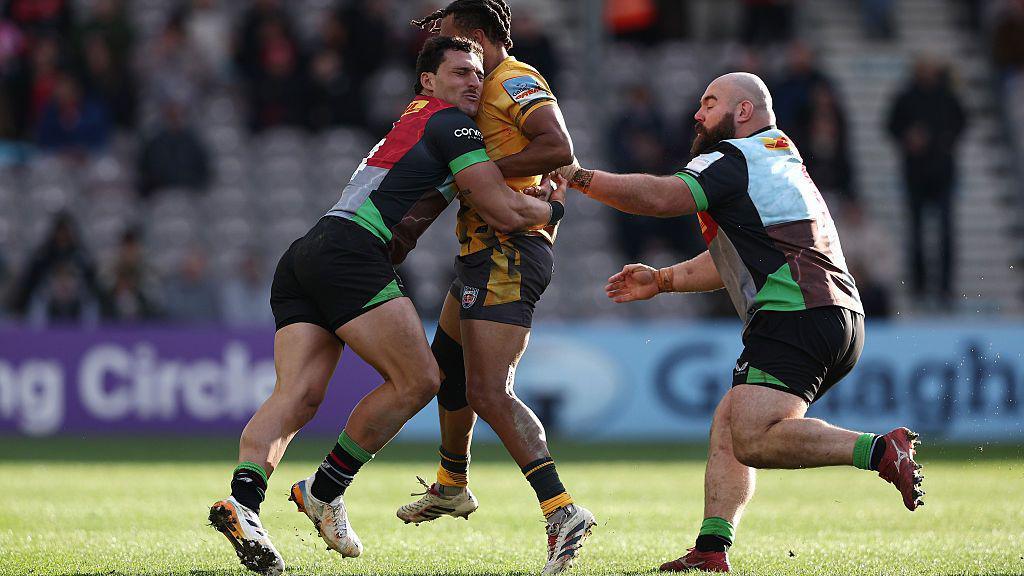 Joe Jones (right) goes in to help a Harlequins team-mate hold up a Newcastle Red Bulls player (centre) during a game
