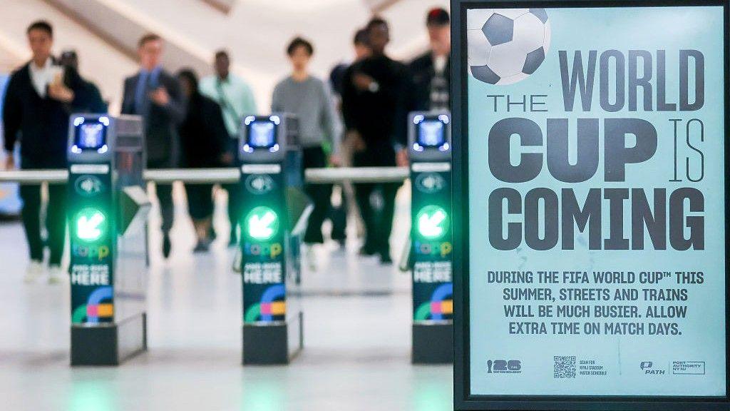 An image of turnstiles with the sign 'The World Cup is coming'