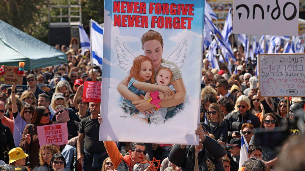 Crowd holds poster of Bibas and two children