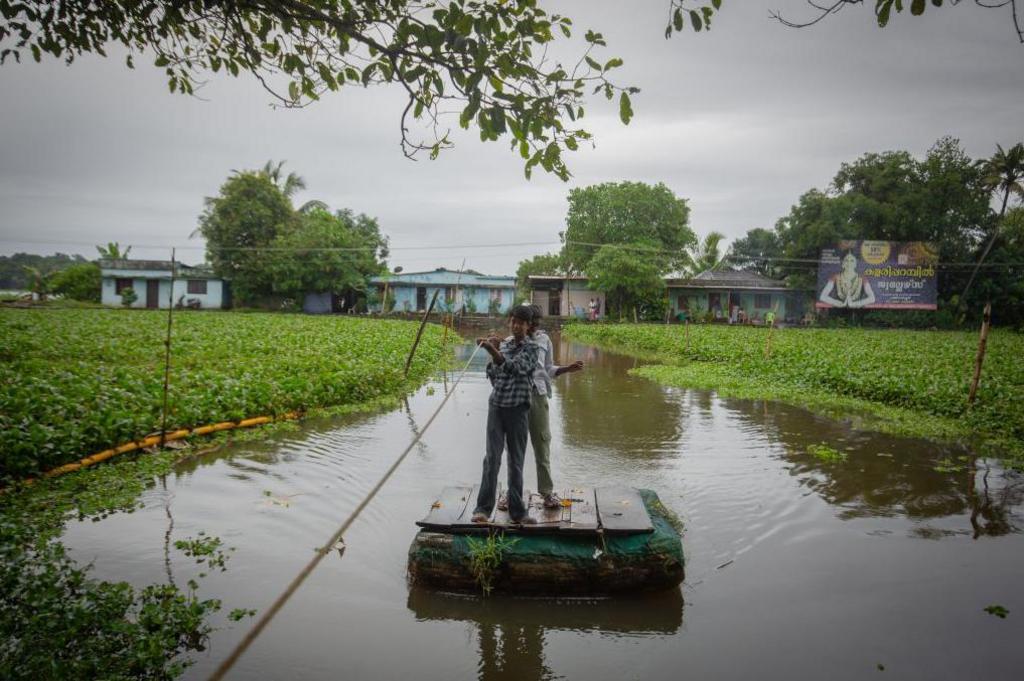 Boys use a makeshift raft to cross a canal in Kerala.