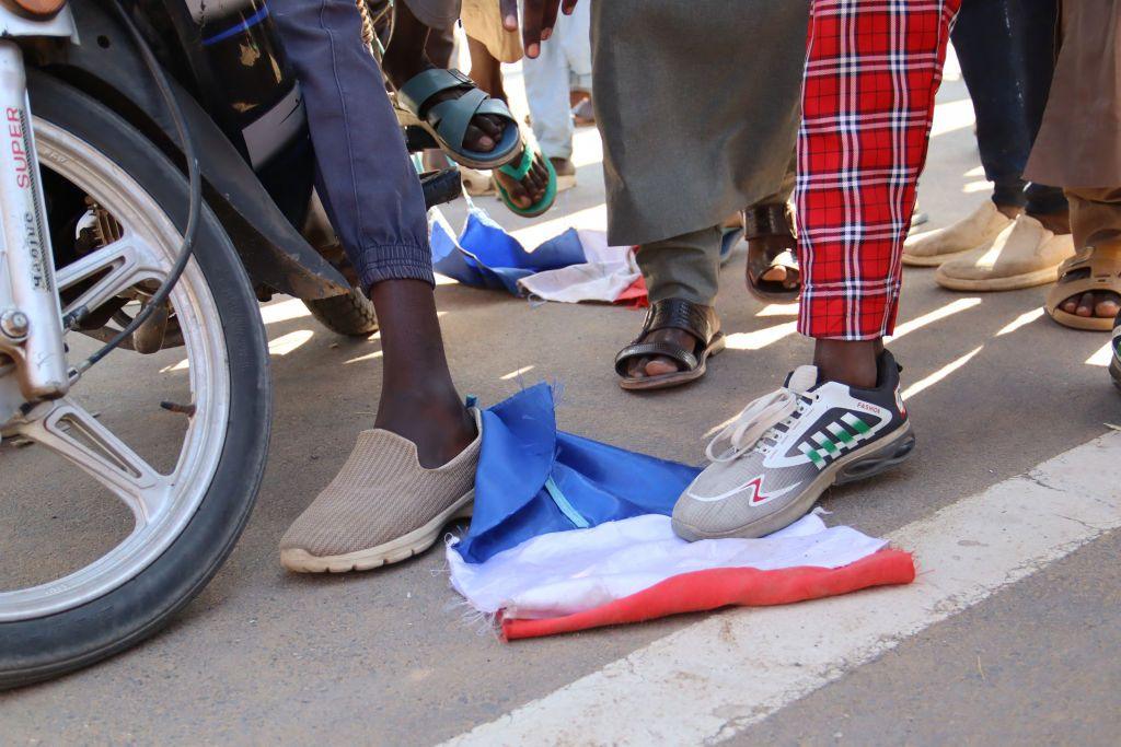 People stamp on a French national flag. Only their legs and feet are visible. On a street in N'Djamena, Chad - Friday 6 December 2024