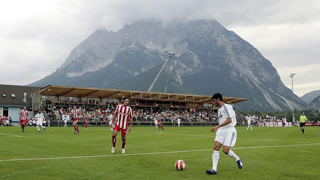 Stoke City play Real Madrid in a small Austrian stadium next to a large mountain, which towers over a low stand of seats