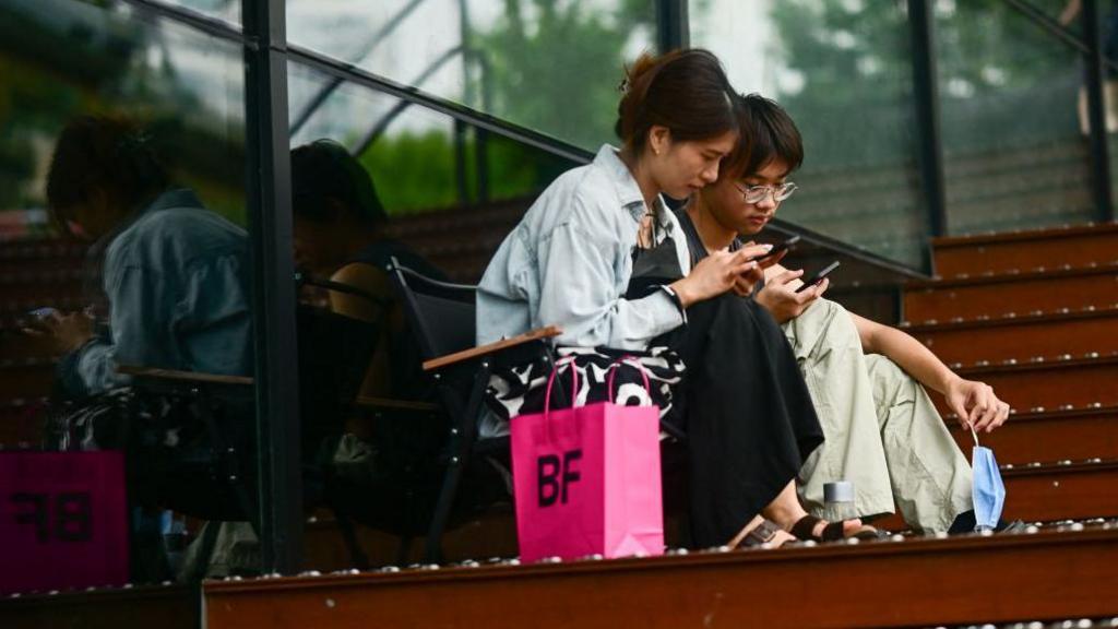 A young woman and man looking at their phones in China 