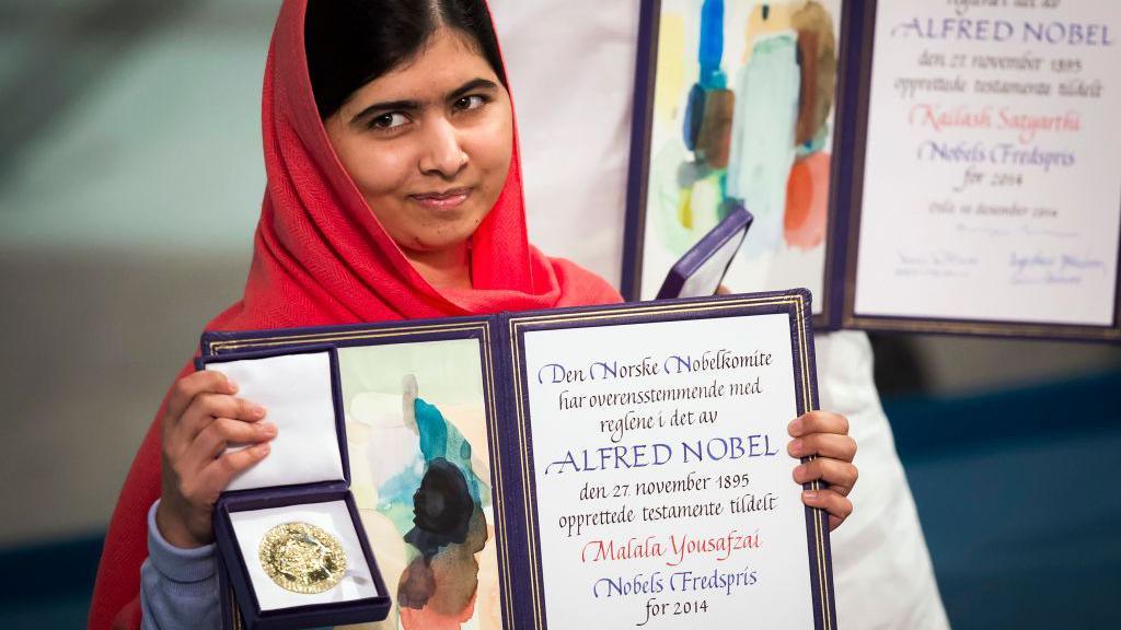 Malala Yousafzai holding her medal and certificate.