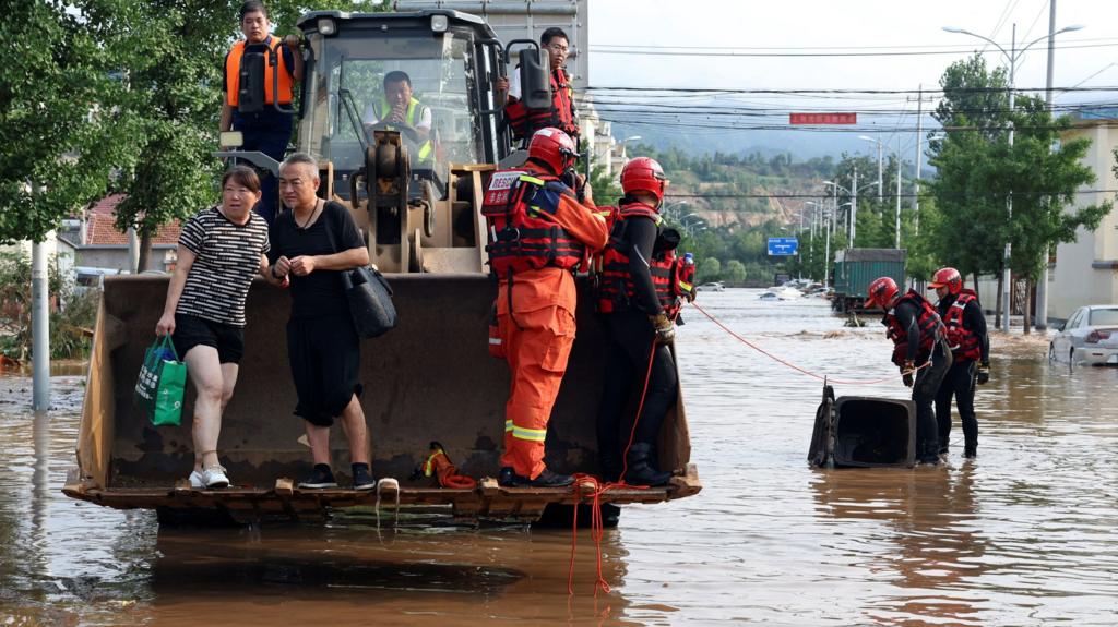 People evacuate floods in Beijing on board an excavator