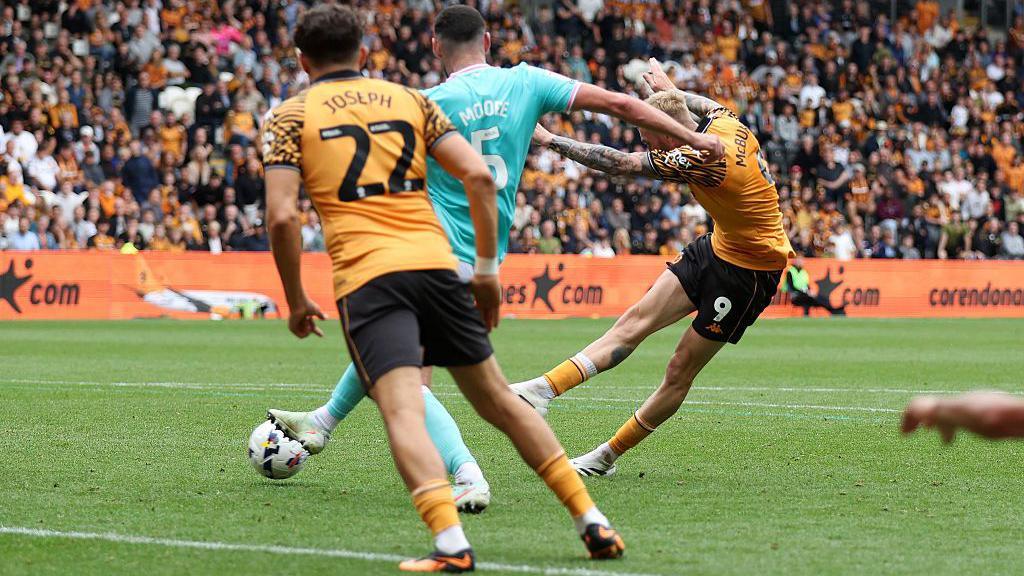 Oli McBurnie scores his first league goal for Hull City with Oxford United defender Elliott Moore attempting to block the shot