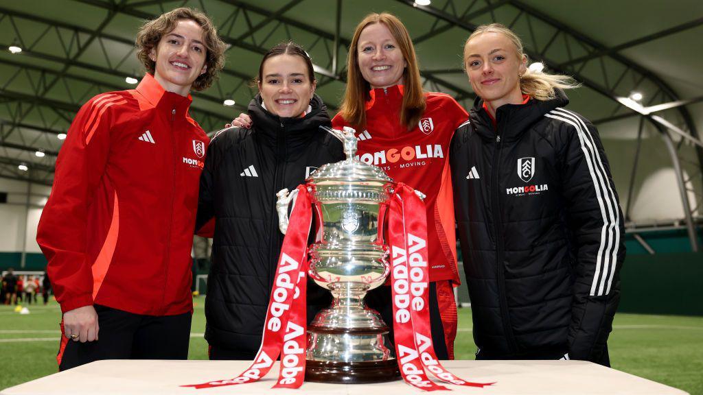 (left to right) Ella Tagliavini, Stella Gandee Morgan, Becky Stormer and Ellen Newman stand and pose with the Adobe Women's FA Cup trophy at Motspur Park before the Women's FA Cup fourth-round tie with London City Lionesses