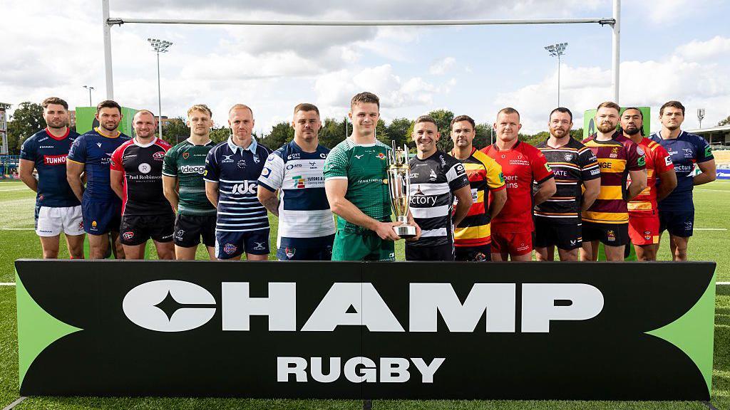 The 14 team captains of all the Champ rugby sides pose with the trophy in front of the Champ Rugby board