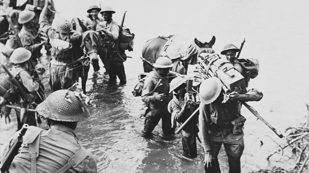 Indian troops of the 26th Indian Brigade, 36th Indian Infantry Division of the British 14th Army unloading ammunition boxes and supplies from pack mules climb the riverbank after crossing the Nammeiit River at Myitson, Burma (Myanmar) during the Burma Campaign against the occupying Imperial Japanese Army, circa March 1945