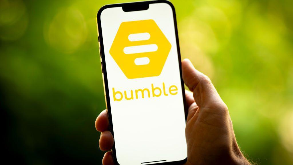 A general picture of a hand holding a smartphone with the Bumble symbol