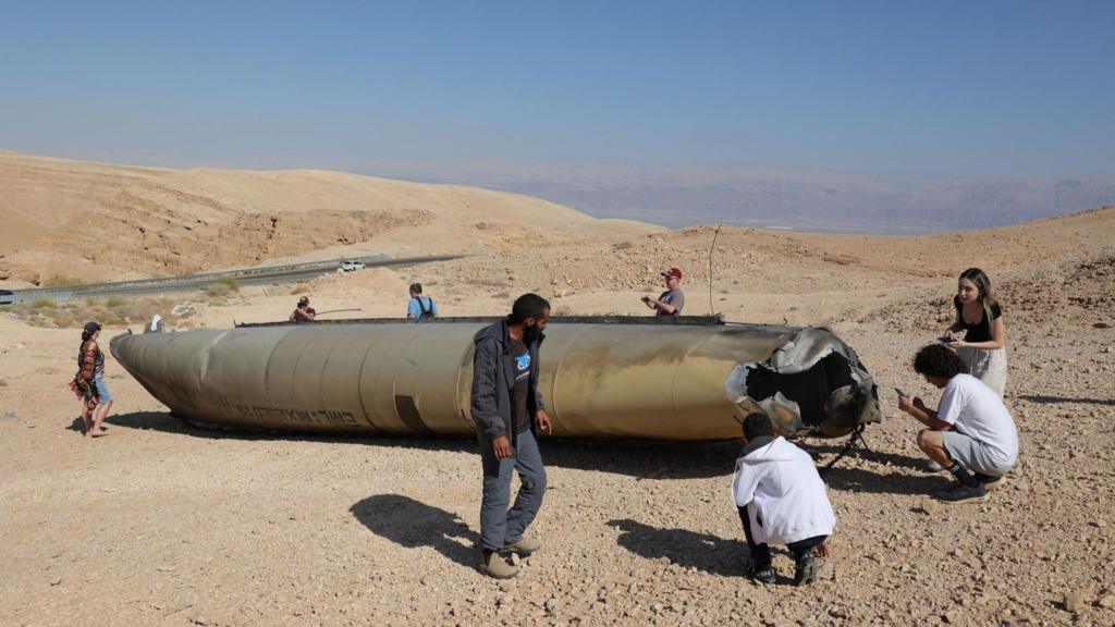 People look at the wreckage of an Iranian ballistic missile in the Negev desert near the Dead Sea, southern Israel, 