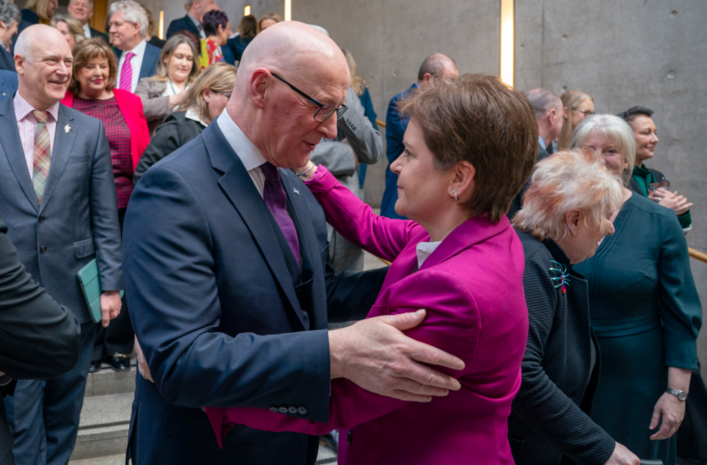 John Swinney and Nicola Sturgeon hug as they are joined by departing MSPs