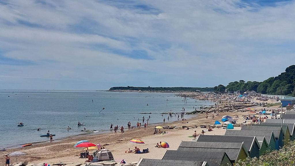 A beach scene with people sitting under sun umbrellas