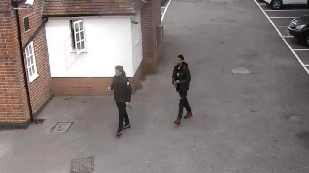 CCTV of Carmody and Barnett dressed in black and walking through a pub car park