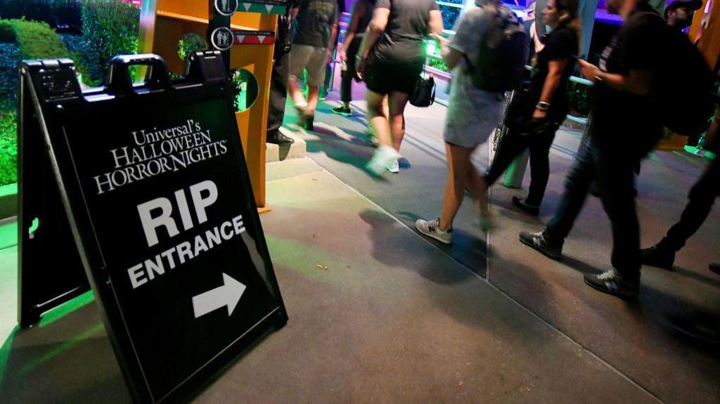 A black sign with white text and an arrow directs visitors to Halloween Horror Nights