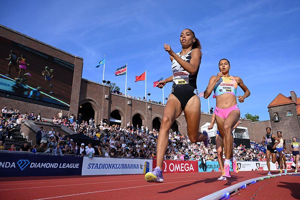 Rachel Klopfenstein of Mauritius and Audrey Werro of Switzerland compete in the Women's 800m at Stockholm Diamond League - they are seen running past a packed small stand of fans in a historic stadium, with fans close to the track.