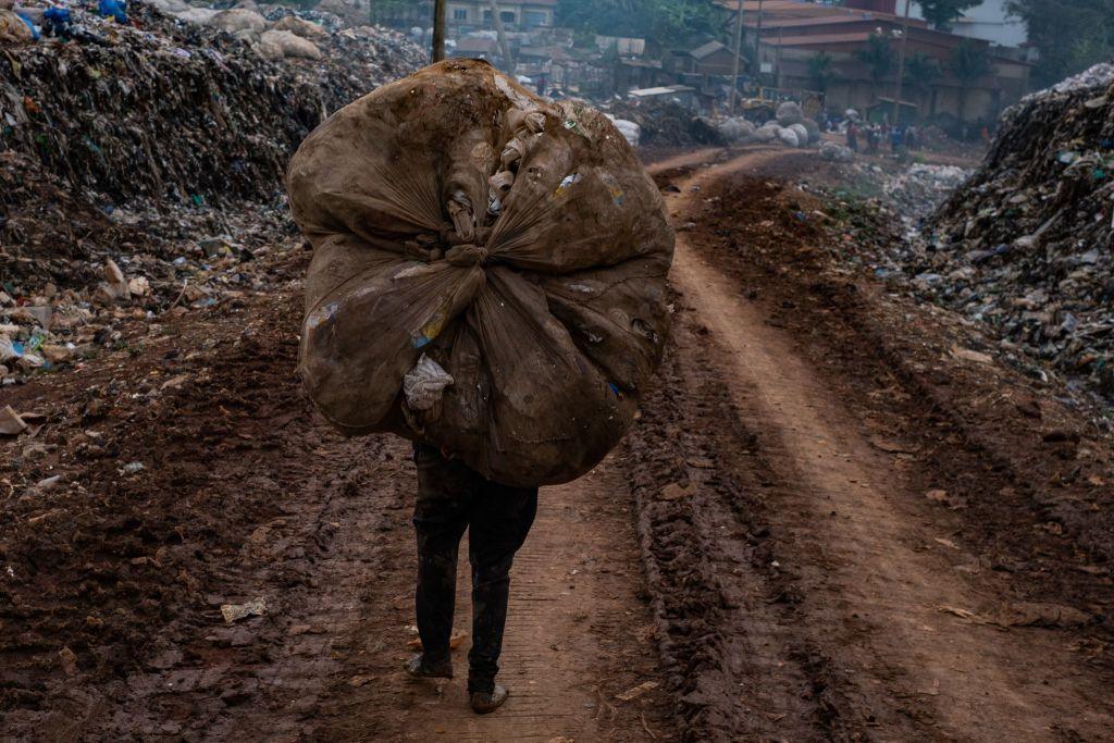 A rubbish collector carrying plastic on his head at a landfill in Kampala 