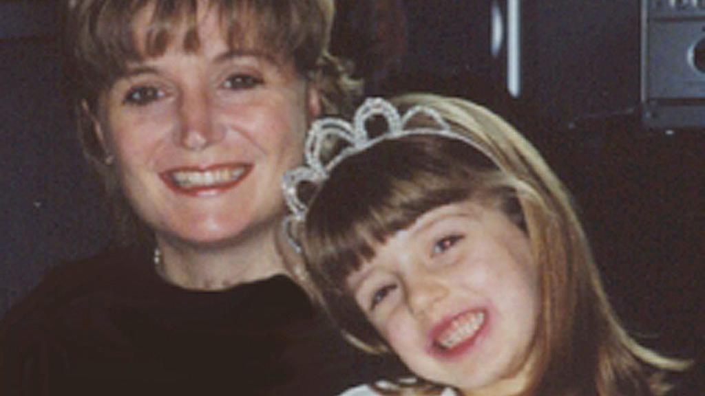 A grainy photo of a woman with blonde hair smiling with a young girl wearing a tiara.