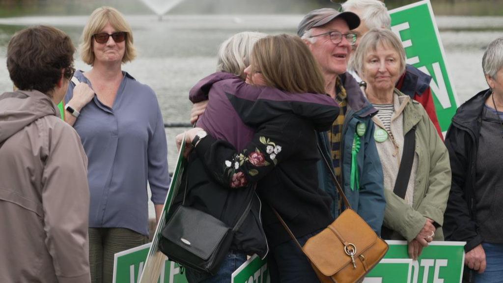 Green Party campaigners hugging each other in Diss after Adrian Ramsey is elected MP