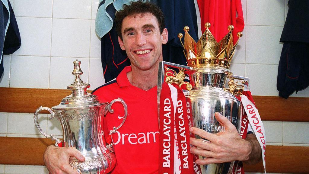 Arsenal defender Martin Keown celebrates with the FA Cup and Premier League trophies after his side did the Double in 2001-02