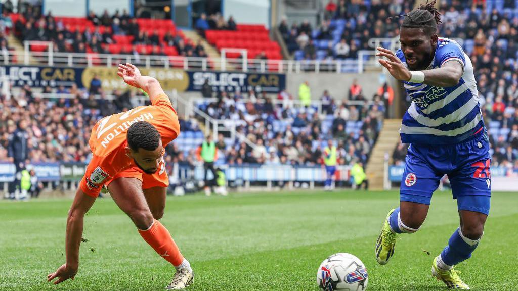 Blackpool's CJ Hamilton stumbles as he runs with the ball under pressure from Reading's Jeriel Dorsett