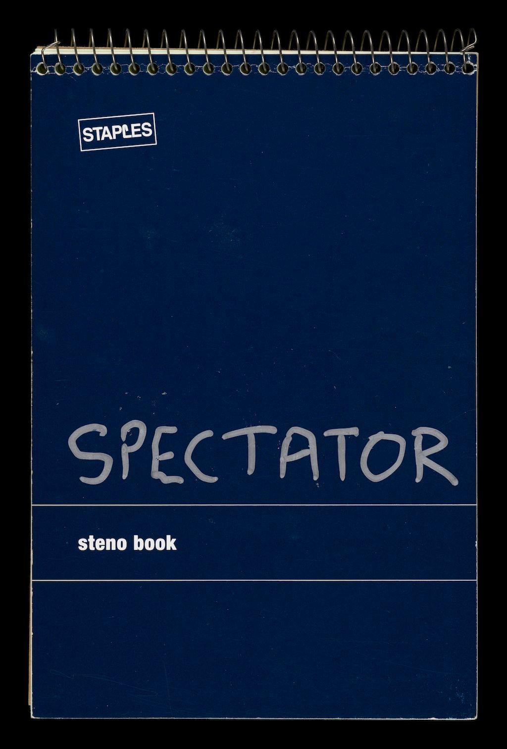 A blue spiral-bound notebook, with the word Spectator written across the front in silver pen