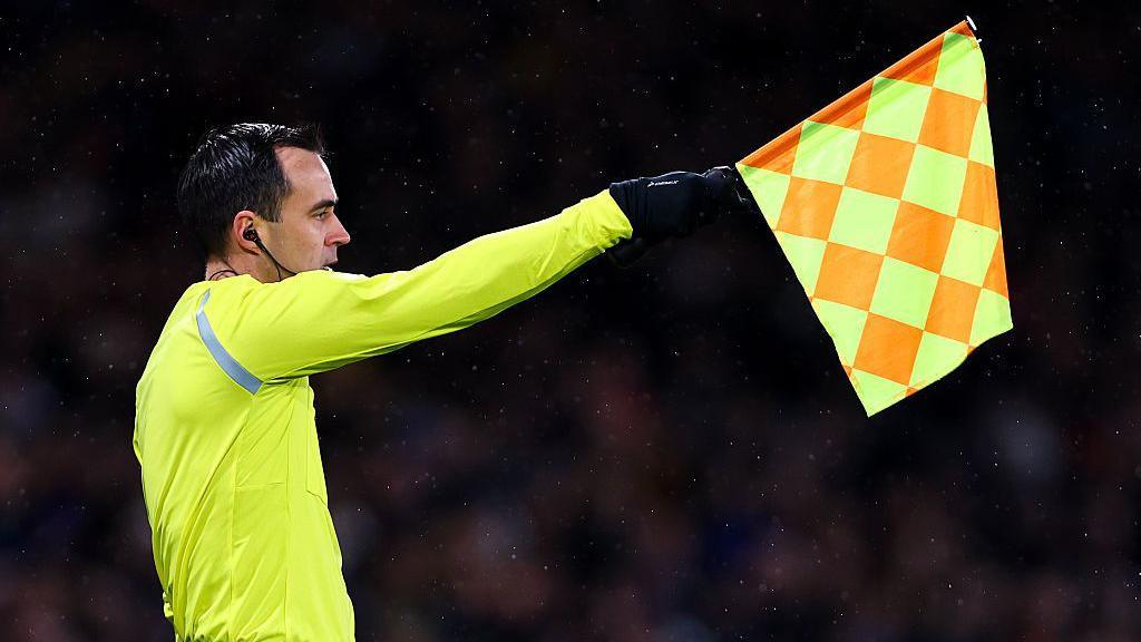 Linesman holding up offside flag during Scotland's World Cup qualifier against Denmark.