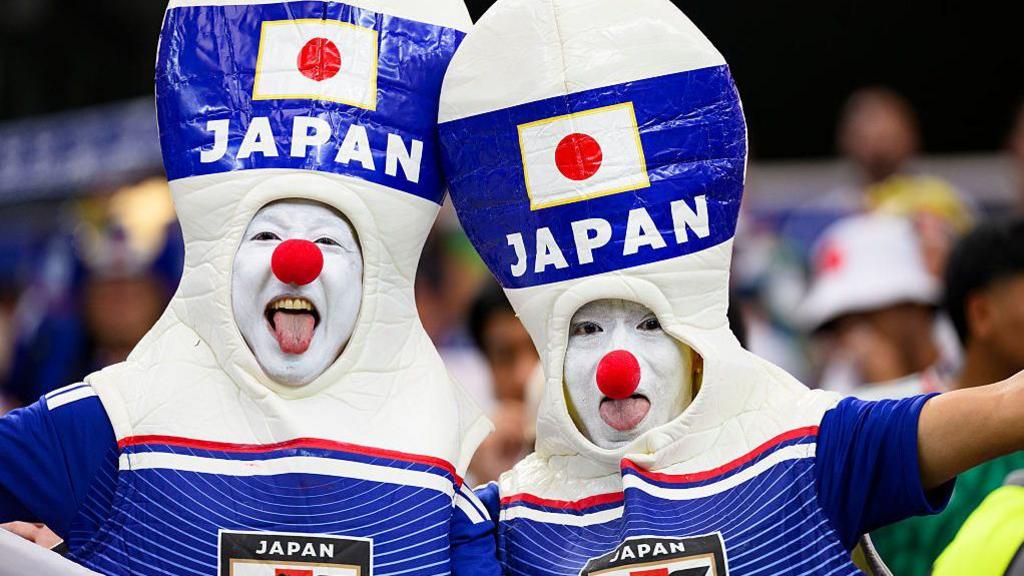 Japan supporters have fun dressed as bowling pins with white faces and red noses.