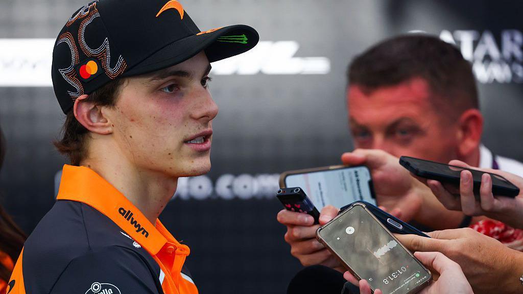 McLaren's Oscar Piastri speaking to journalists, many of whom are holding up phones to record the interview, following the United States Grand Prix