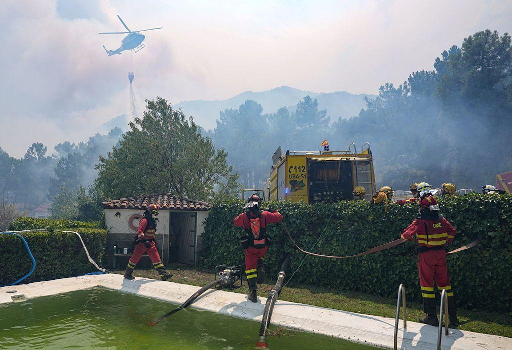 Firefighters stand next to a swimming pool. 