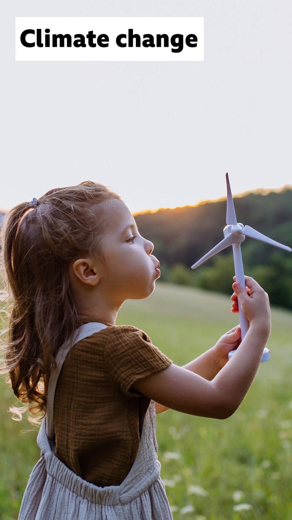 A young girl blowing a model of a windmill