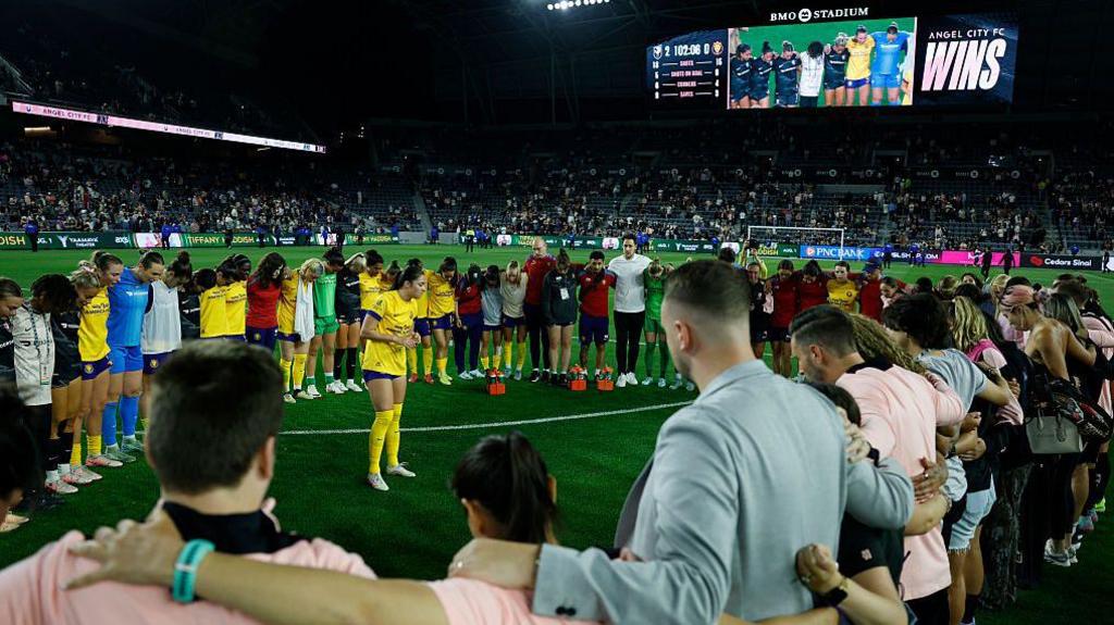 Players and backroom staff from Angel City and Utah Royals form a 'prayer circle'