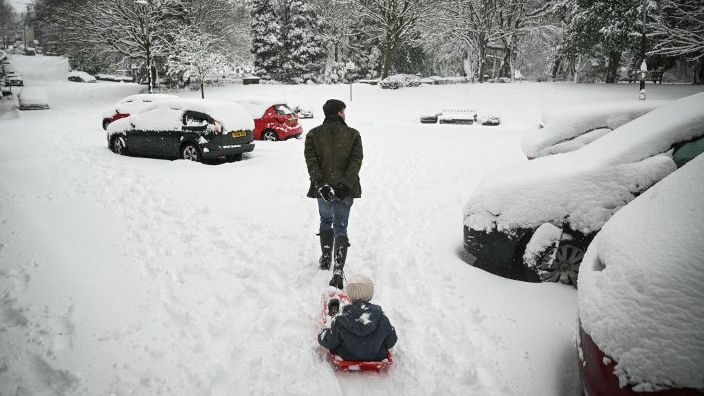 man pulling a child in a sledge on snow