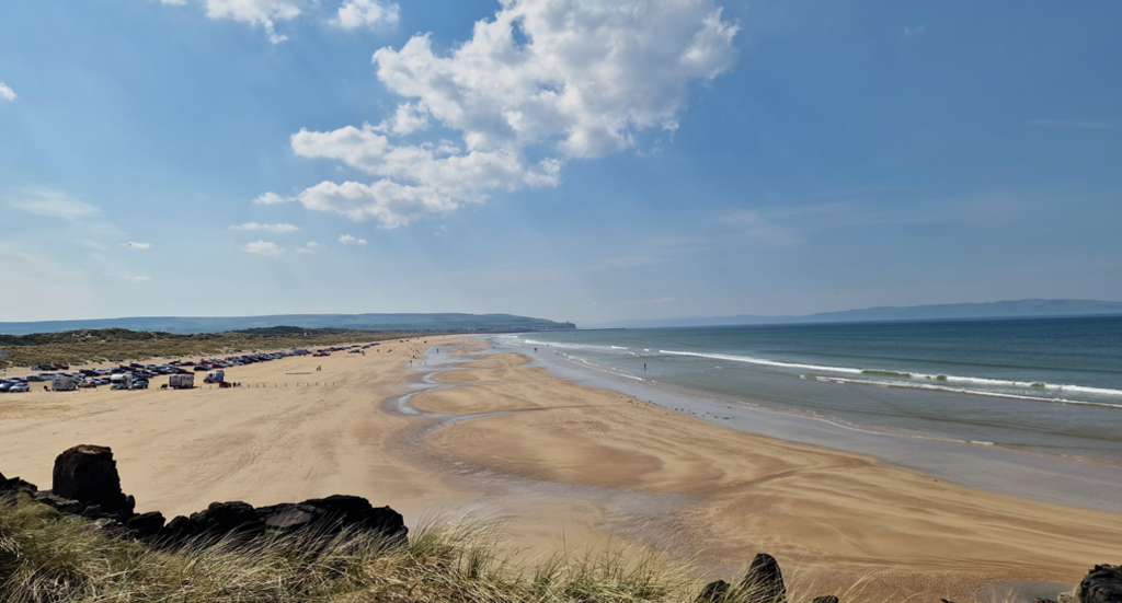 The view at Portstewart, with a sandy beach in the foreground and blue water to the right.