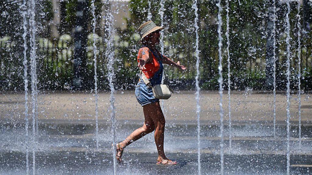 A woman cools off in a fountain in France