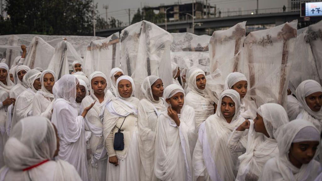 Begena players (a traditional ten-stringed box-lyre instrument) cover their instruments from the rain during celebrations to mark the Ethiopian Orthodox holiday of Meskel, in Addis Ababa, on September 26, 2024.