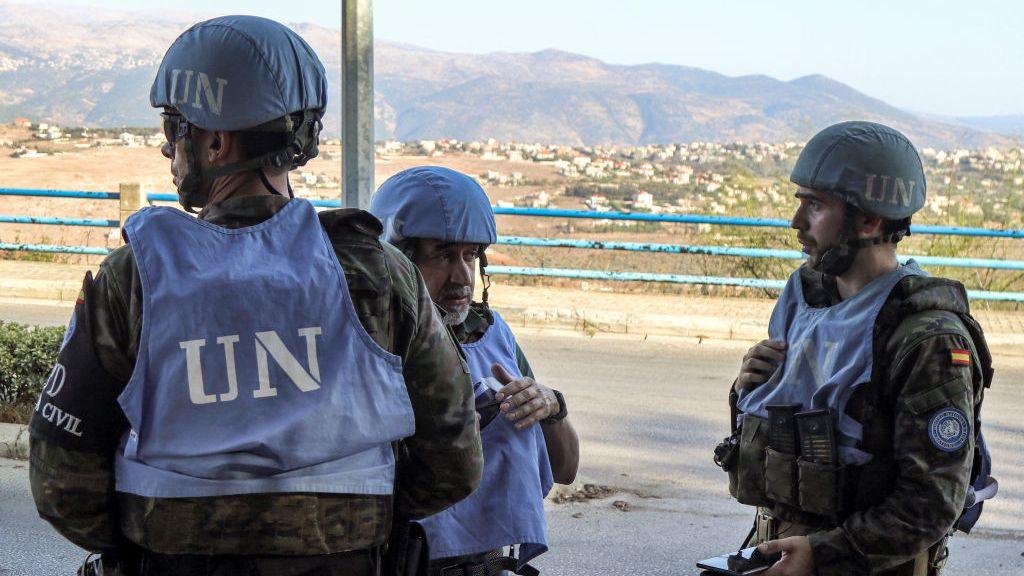 UN peacekeepers in blue bibs and blue hats with 'UN' emblazoned on them, stand on a road in southern Lebanon