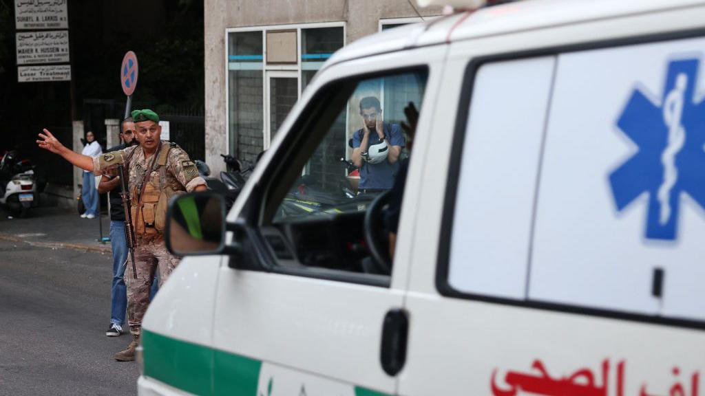 A Lebanese army soldier gestures to an ambulance rushing wounded people to a hospital in Beirut