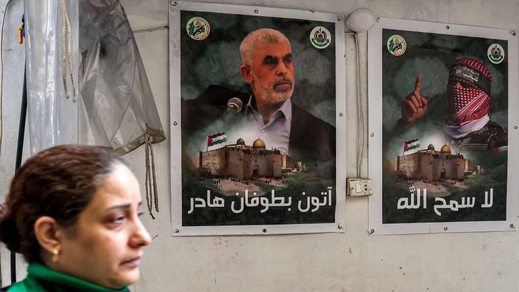 A woman walks past posters depicting Yahya Sinwar (left) in the Gaza Strip.